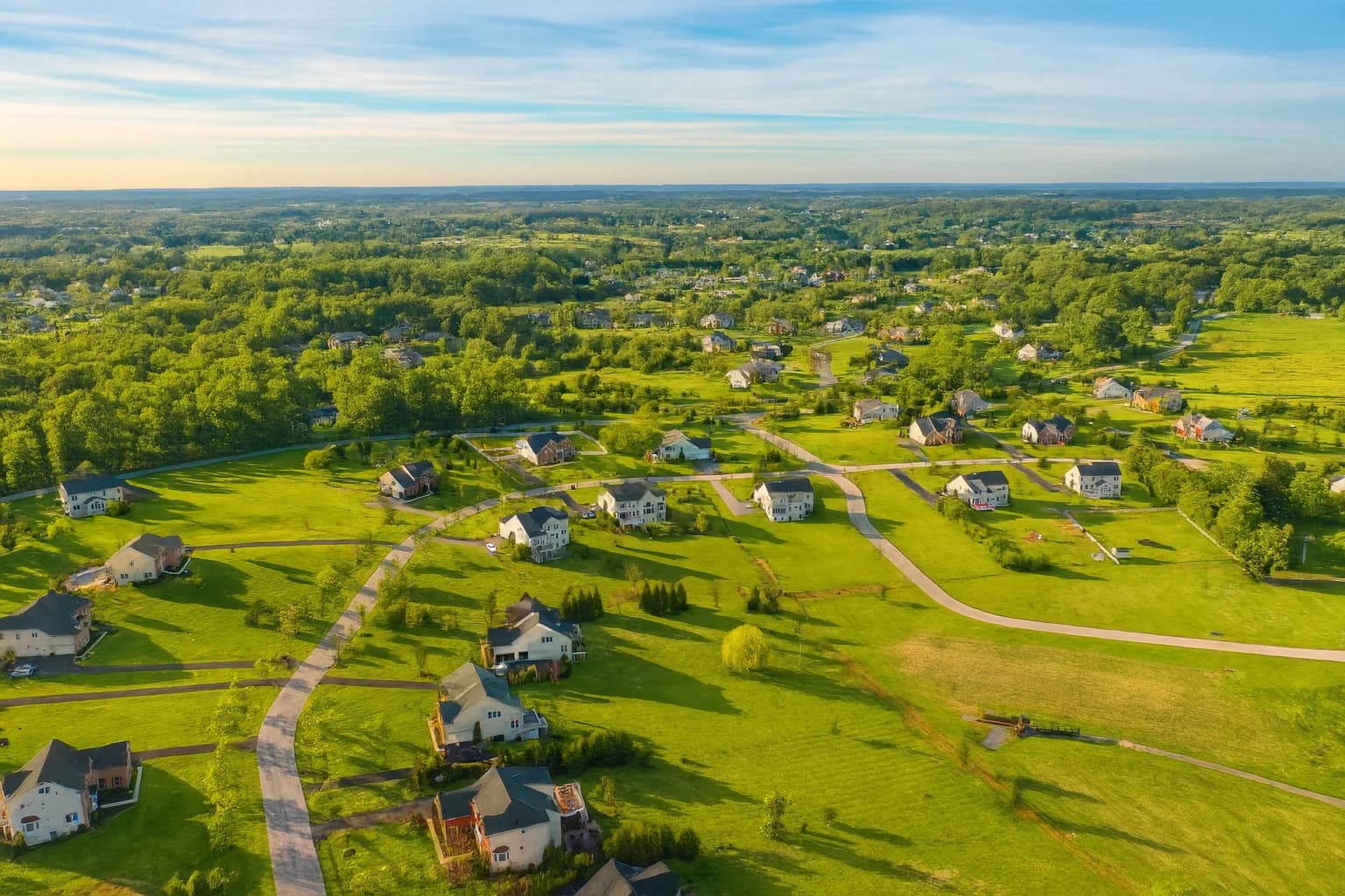 An aerial view of Warfields II homes and fields at sunset